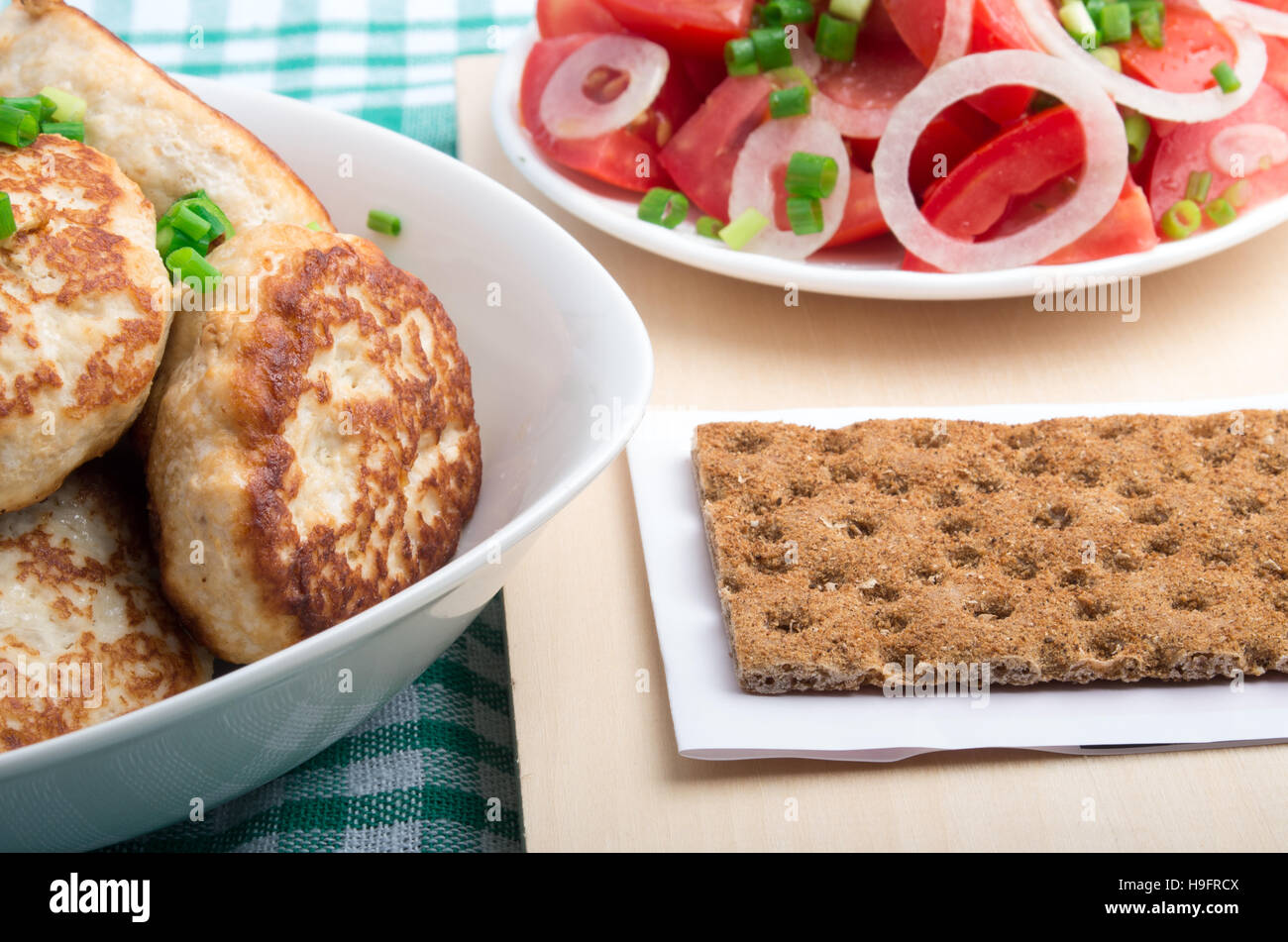 Cuisine maison russe - gros plan avec des poireaux filet de poulet, le pain de seigle et une salade de tomates fraîches, les poireaux et l'oignon sur une nappe verte Banque D'Images