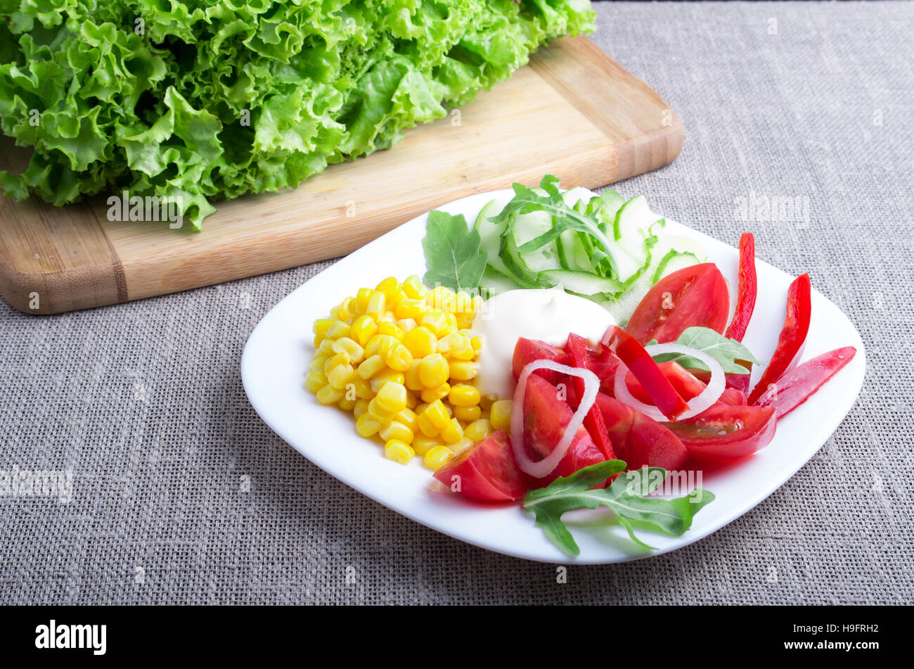 Salade de tomates naturelles utiles, de la mozzarella fromage, concombres, maïs, la laitue et la salade ruccola sur fond de nappe gris Banque D'Images
