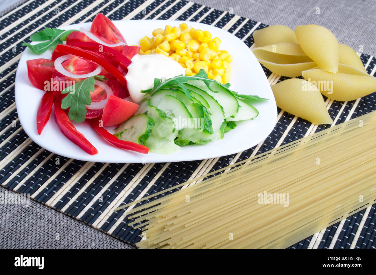 Vue rapprochée d'un plat végétarien de légumes crus et près de la mozzarella et pâtes spaghetti italien sur un fond rayé Banque D'Images