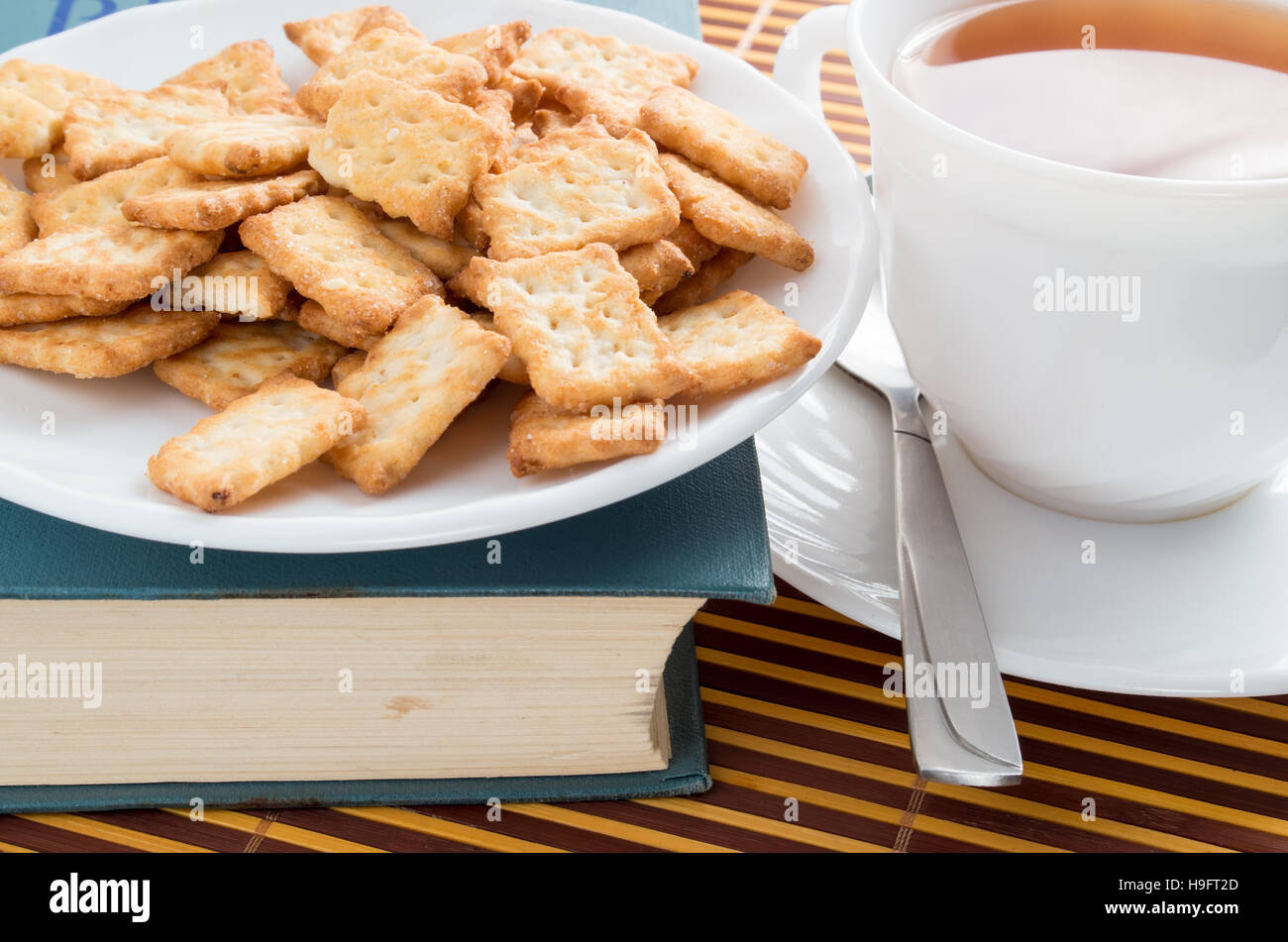 Voir Gros plan sur une tasse de thé et biscuits secs sur un vieux livre Banque D'Images