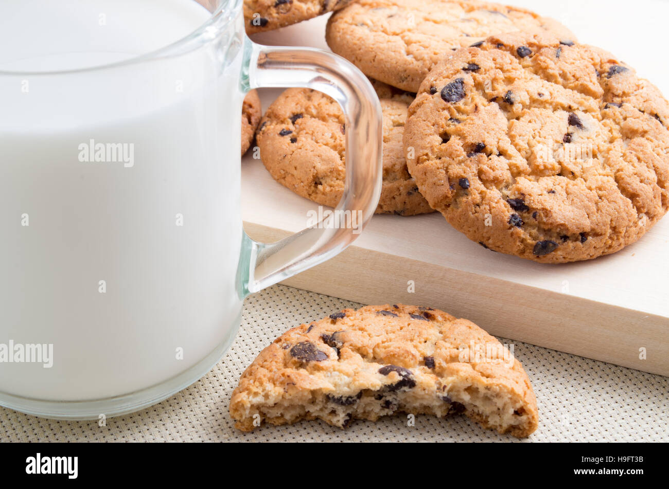Tasse en verre de lait et biscuits aux pépites de chocolat close-up sur plateau en bois avec une faible profondeur de foyer Banque D'Images