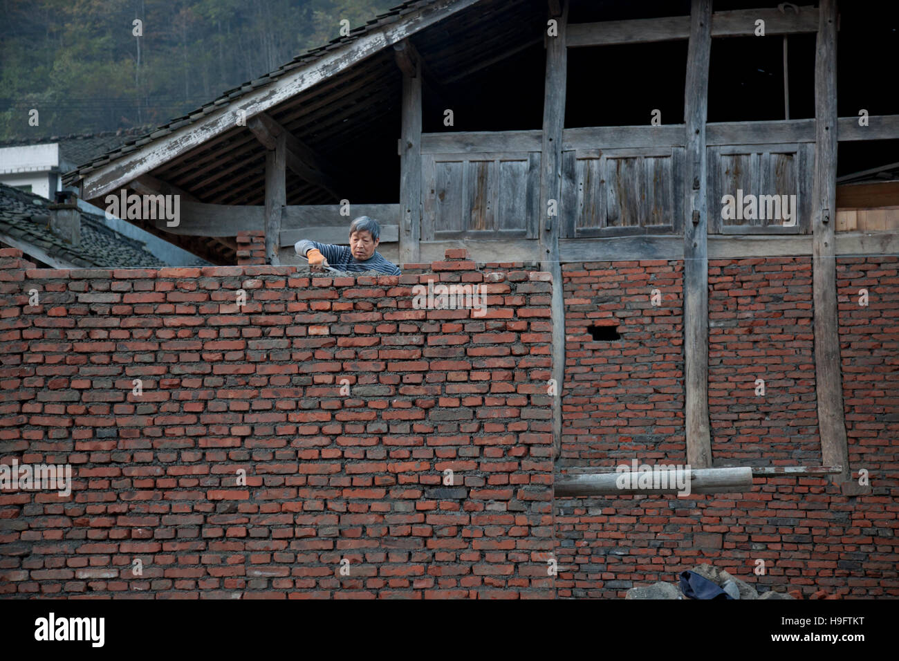 Un agriculteur à construire sa maison privée avec des briques et du bois dans un petit village isolé dans les montagnes de l'ouest de la Chine. Banque D'Images