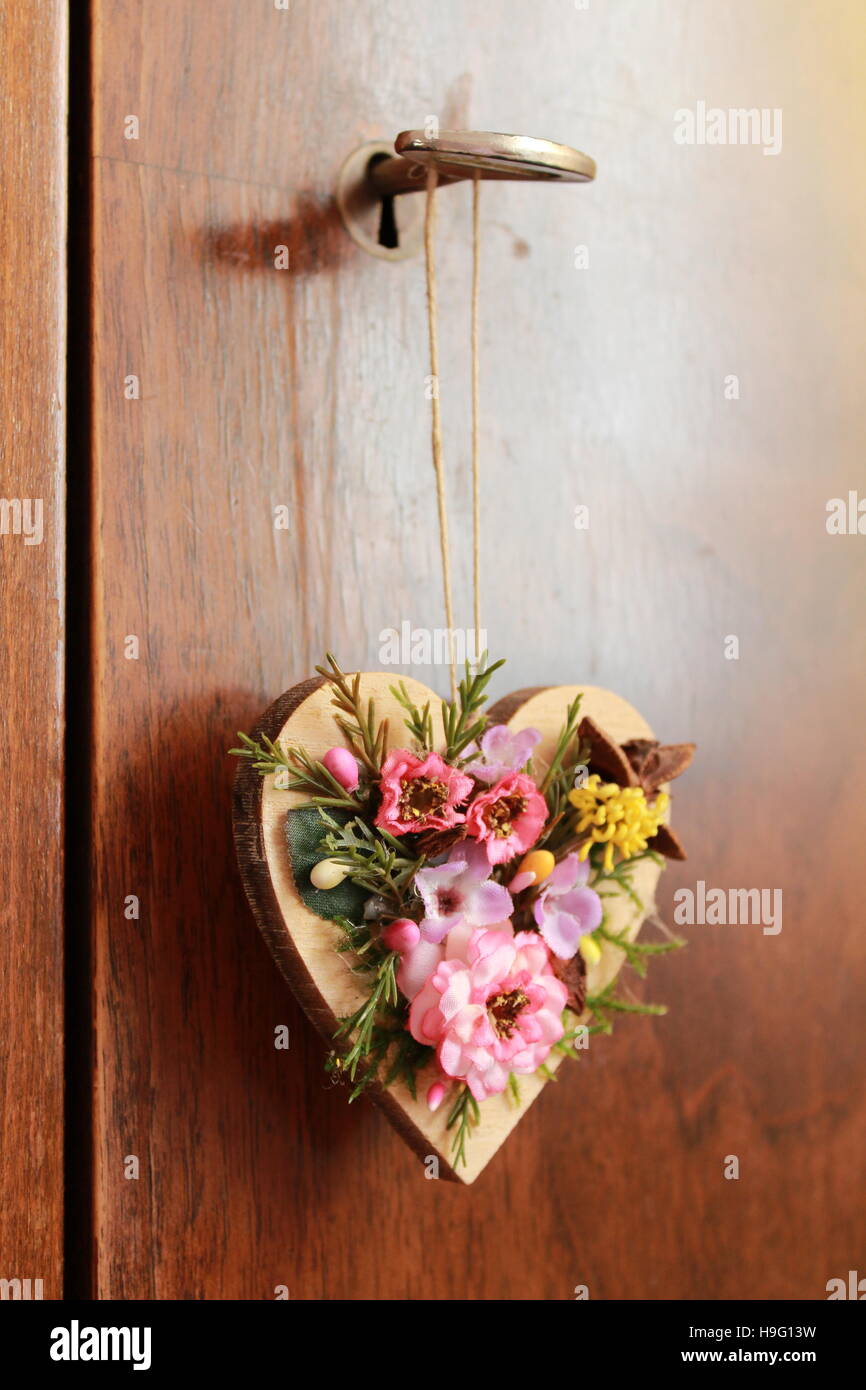 Coeur en bois orné de fleurs artificielles accroché sur la porte de placard Banque D'Images