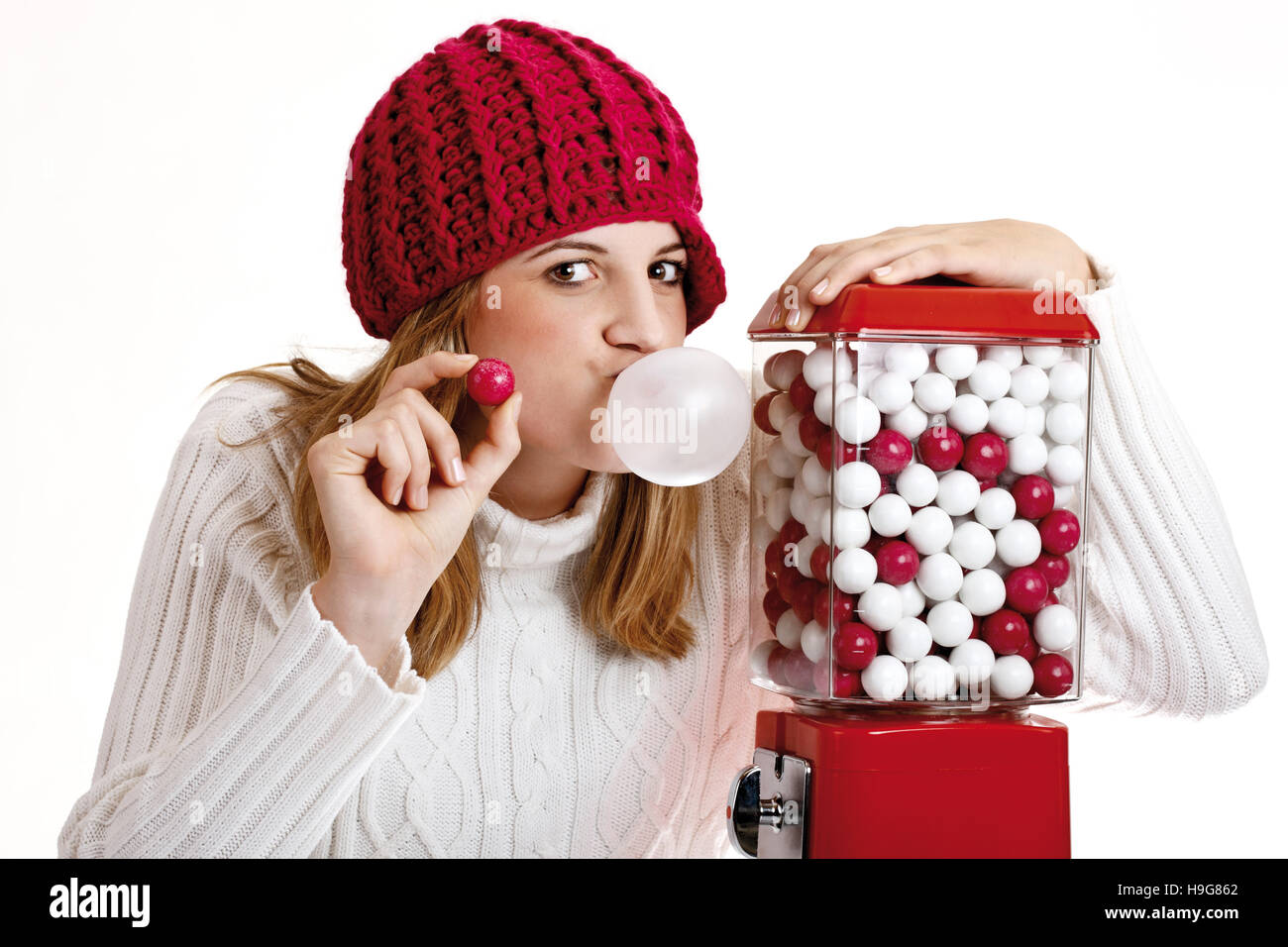 Jeune femme tenant un chewing-gum, à côté d'un gumball machine Banque D'Images