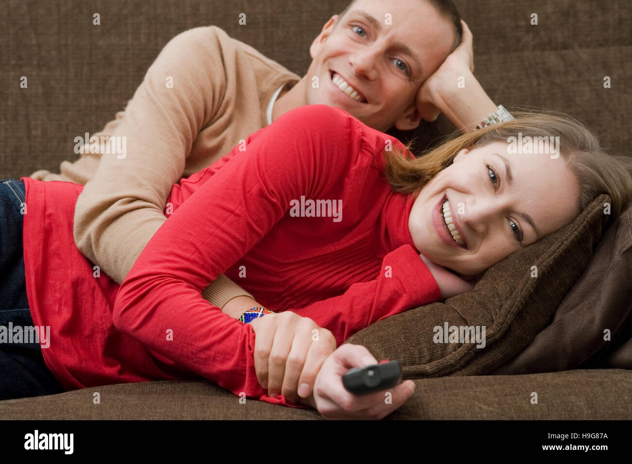 Couple lying on a couch watching TV Banque D'Images