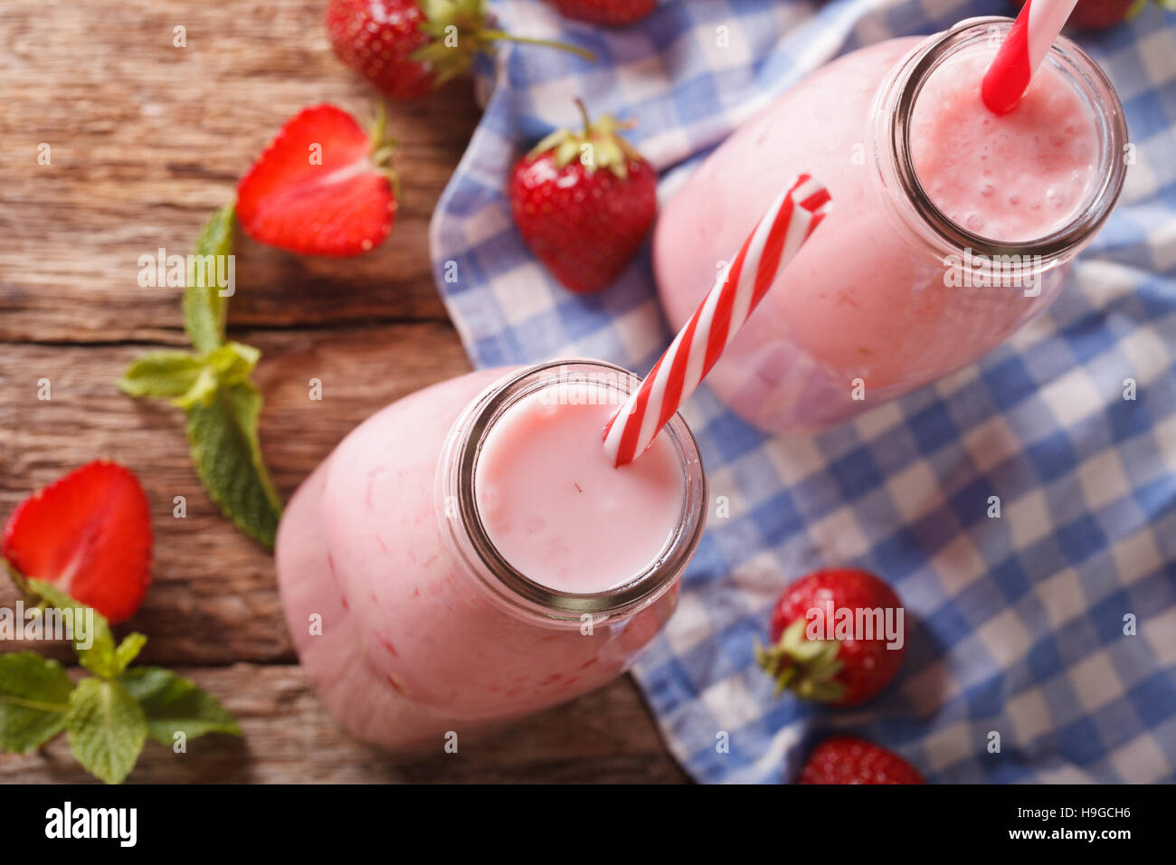Lait frappé aux fraises fraîches dans des bouteilles en verre sur la table. Vue du dessus horizontale Banque D'Images