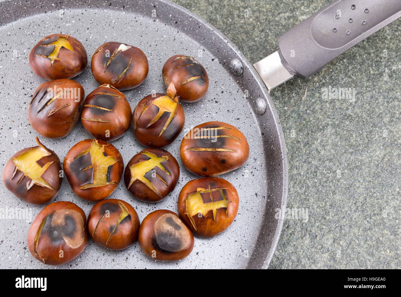 Châtaignes grillées sur un plat de cuisson en pierre Banque D'Images