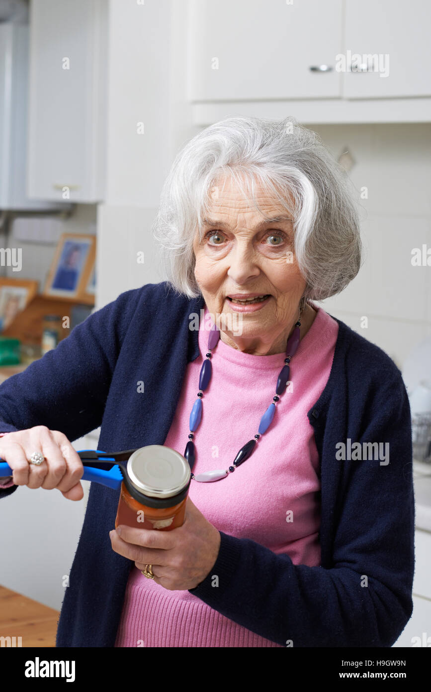 Senior Woman Taking Couvercle de récipient à l'aide de cuisine Banque D'Images