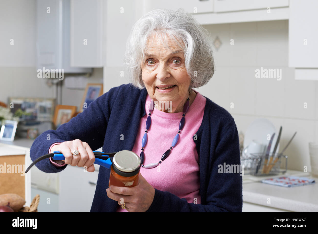 Senior Woman Taking Couvercle de récipient à l'aide de cuisine Banque D'Images