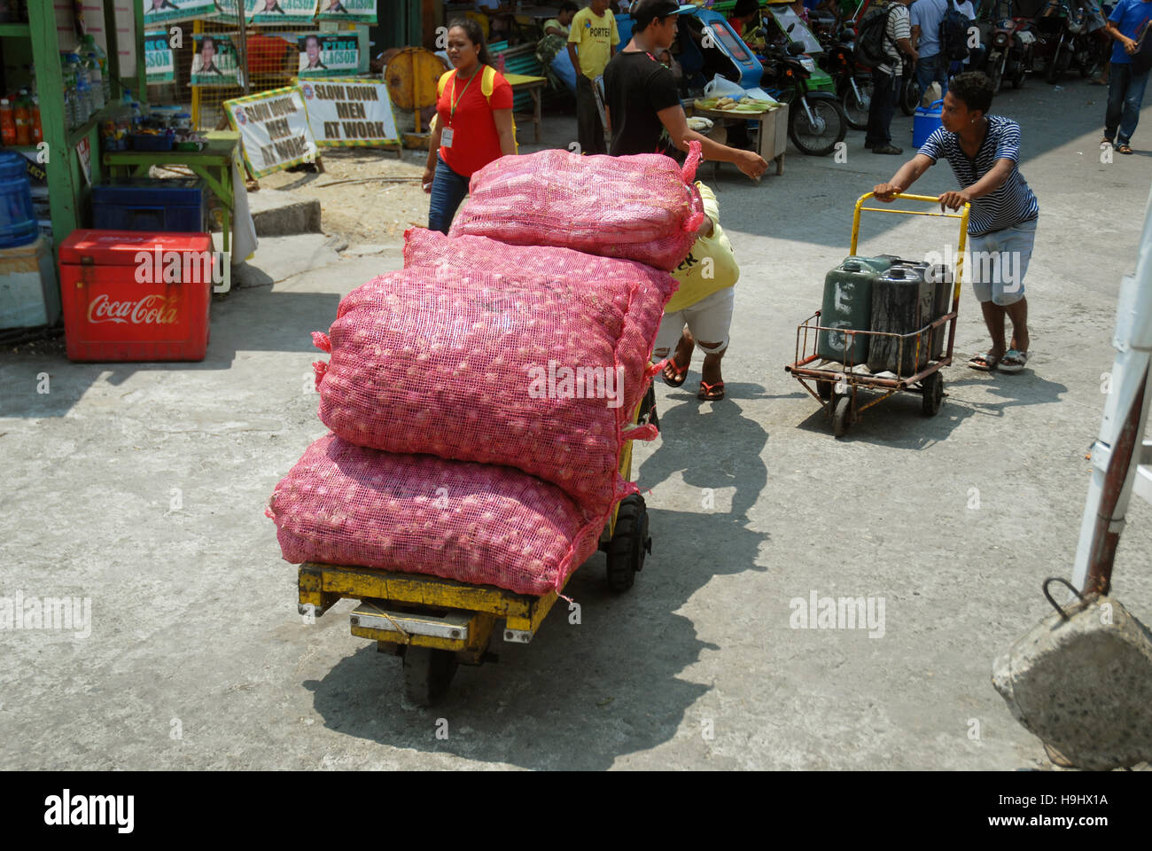 Man pushing trolley avec gros sacs d'oignons, le port d'IloIlo, Philippines. Banque D'Images
