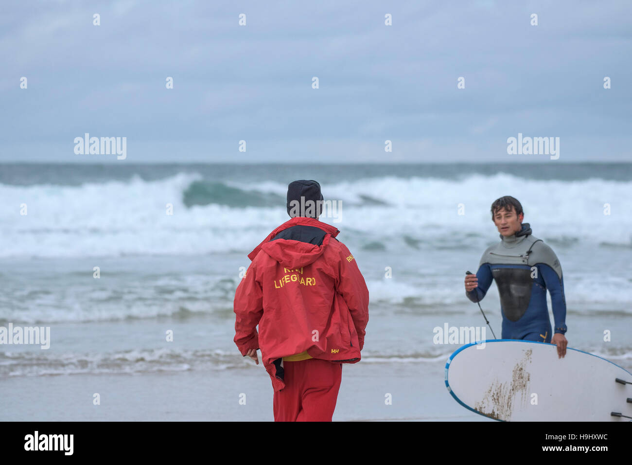 Un sauveteur RNLI parlant à un surfeur sur la plage de Fistral, Newquay, Cornwall. Banque D'Images