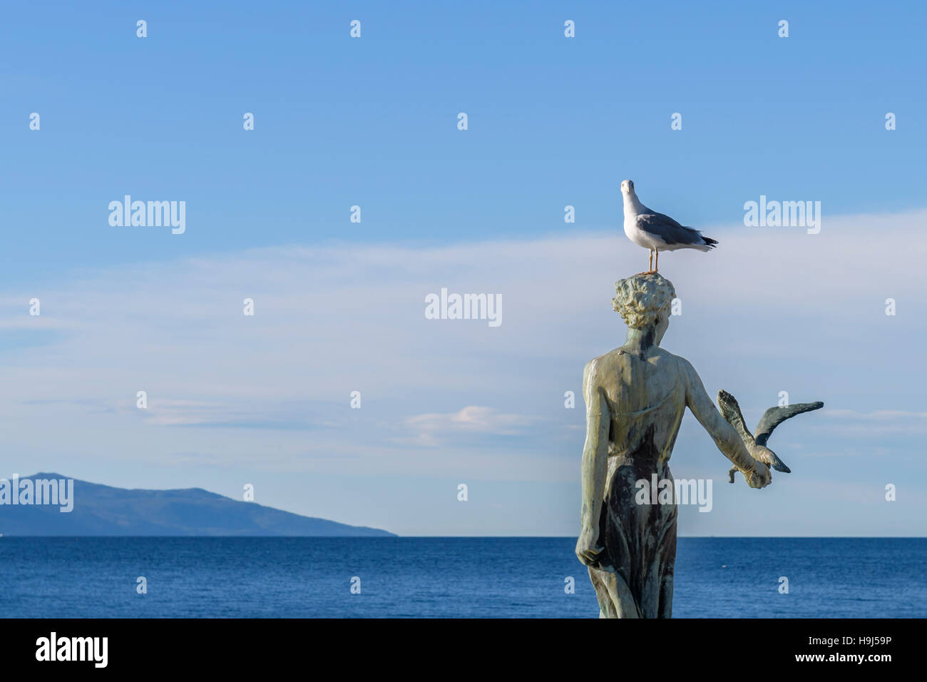 Fille de jeune fille tenant un goéland et face à la mer, statue sur les roches, Opatija, Croatie Banque D'Images