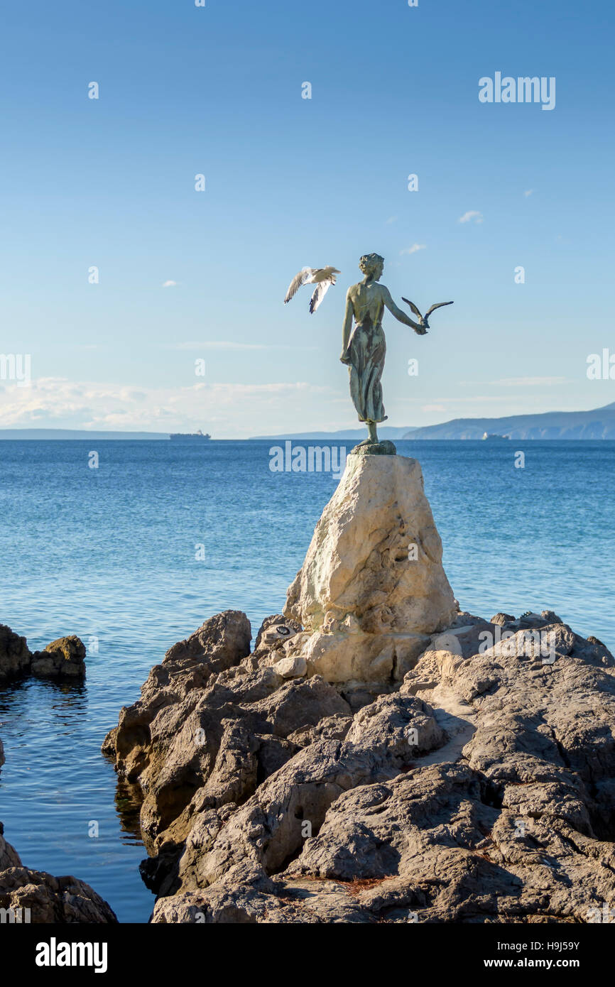 Fille de jeune fille tenant un goéland et face à la mer, statue sur les roches, Opatija, Croatie Banque D'Images