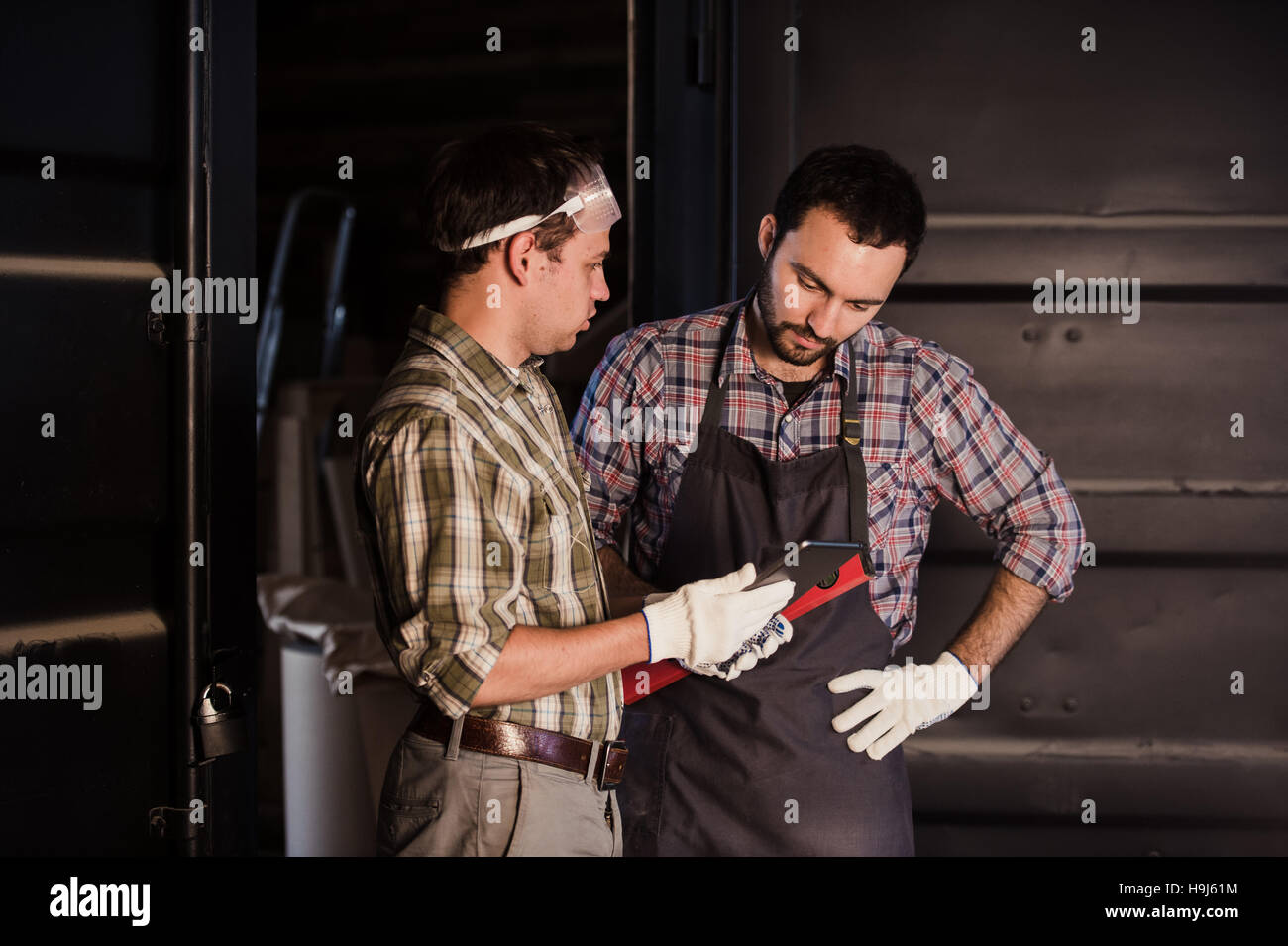 Profession, les hommes et la technologie concept - deux ouvriers avec tablette PC ordinateur en atelier Banque D'Images