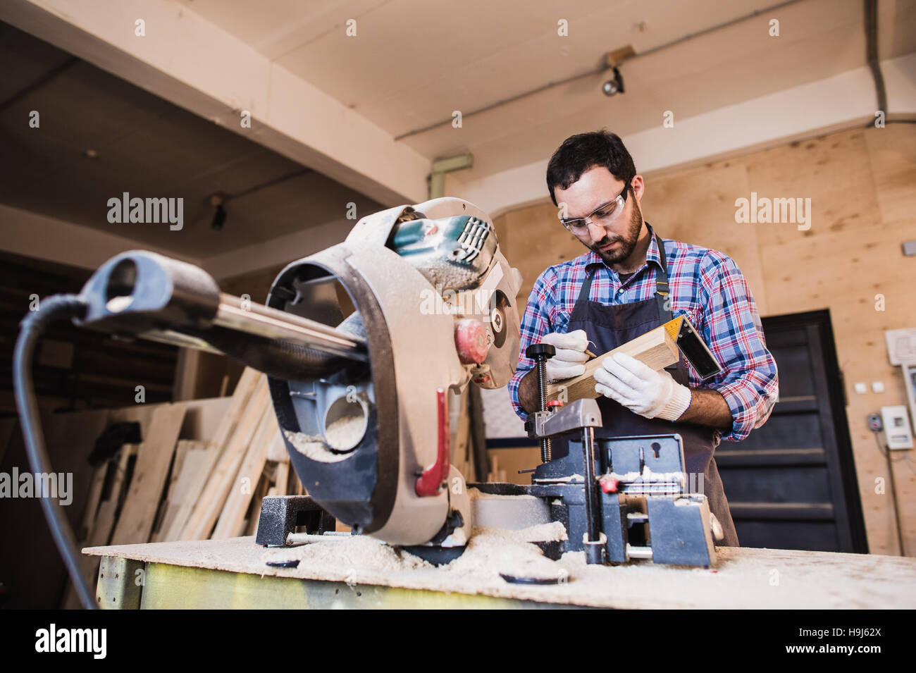 À l'aide d'un entrepreneur d'encadrement tronçonneuse circulaire pour ajuster la longueur des poteaux en bois. Banque D'Images