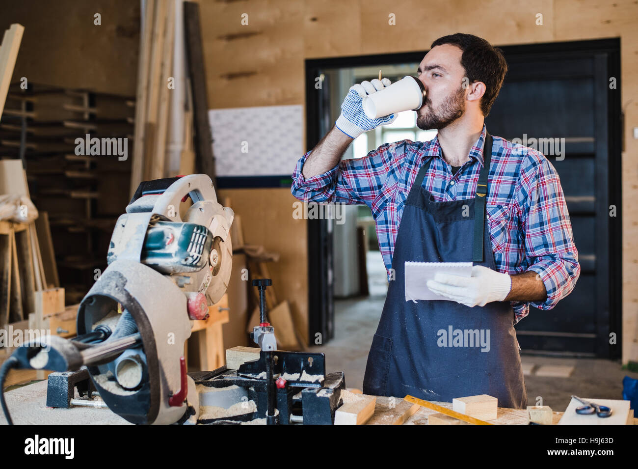 Carpenter en prenant une pause-café holding notebook en face de scie circulaire dans son atelier Banque D'Images