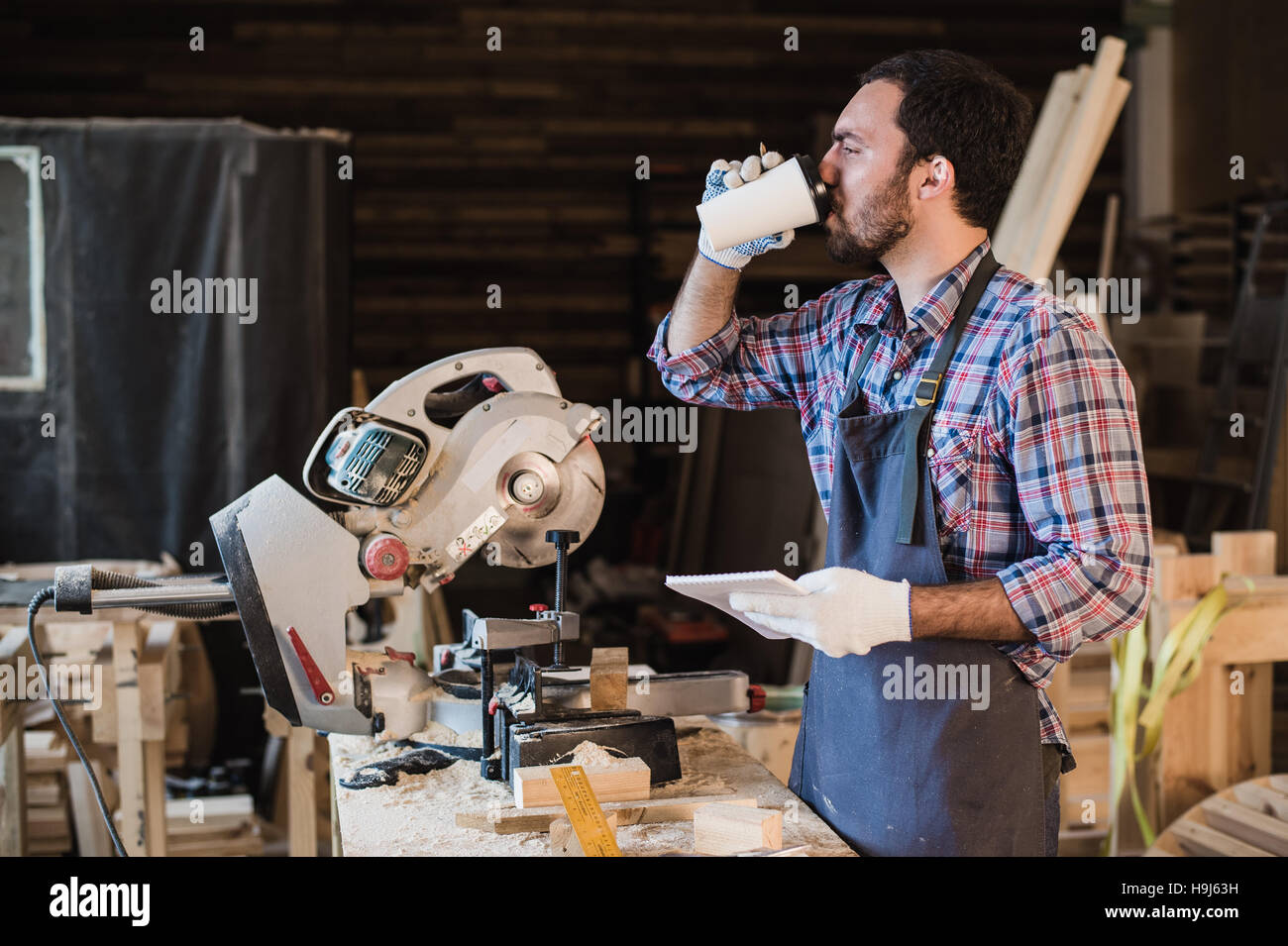 Carpenter en prenant une pause-café holding notebook en face de scie circulaire dans son atelier Banque D'Images