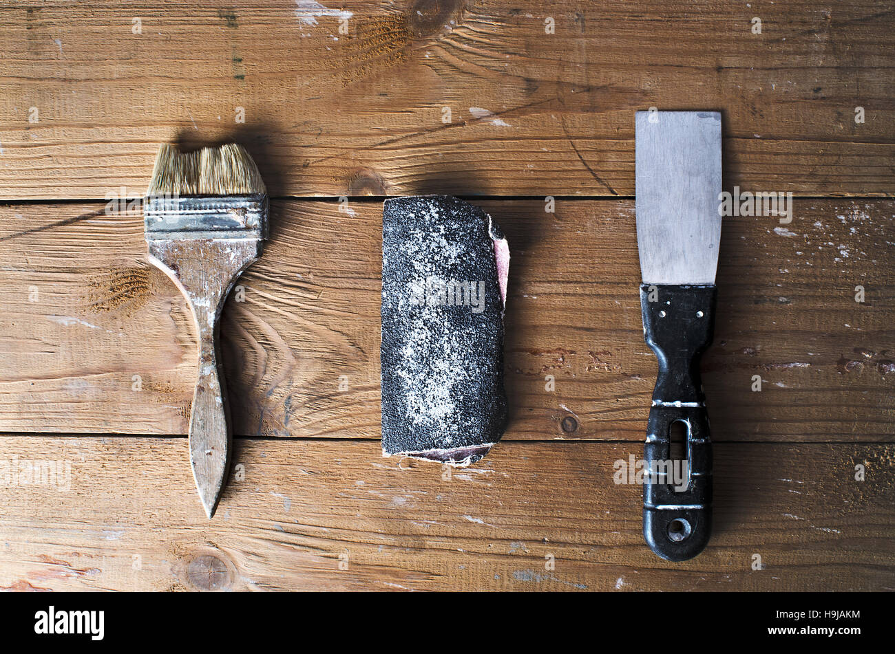 Ancienne brosse, papier de verre et d'une truelle sur un fond de bois en lambeaux brun, vue du dessus, travaux de menuiserie, les réparations à domicile Banque D'Images