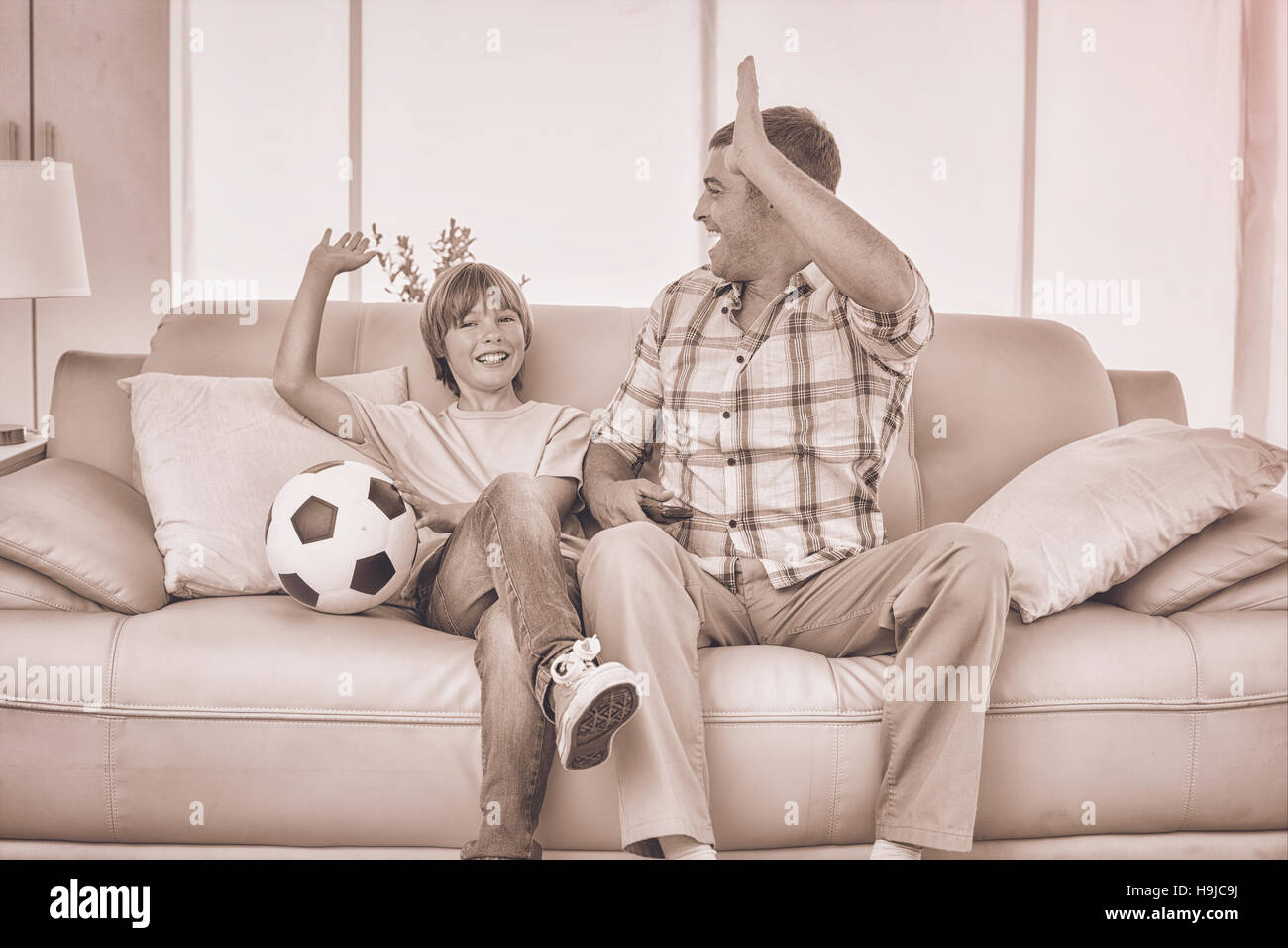 Père et fils de haut donnant cinq tout en regardant un match de football Banque D'Images