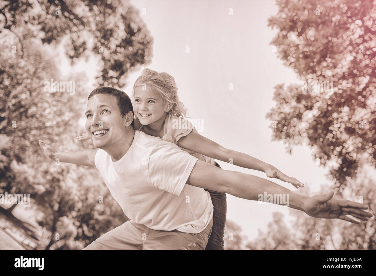 Father giving daughter un piggy back in park Banque D'Images