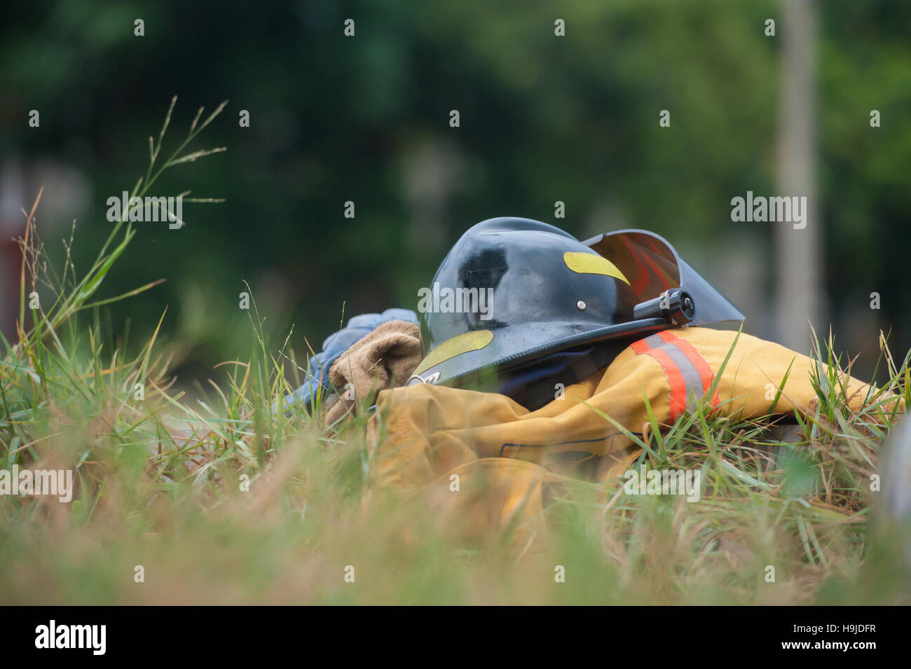 La lutte contre le feu de protection robuste en tissu, gants, casque, manteau, pantalon, sur fond d'herbe verte Banque D'Images