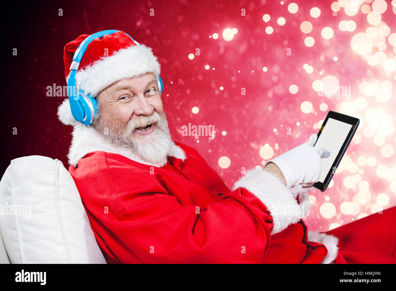 Image composite du portrait du père noël listening music with digital tablet Banque D'Images