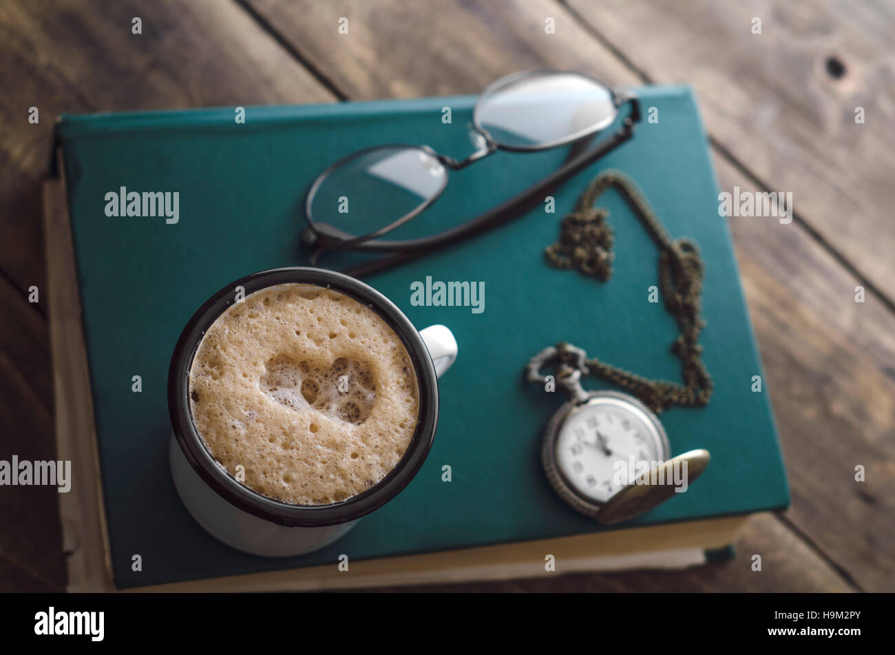 Vintage montre de poche avec tasse de café sur le vieux livre, gros plan Banque D'Images