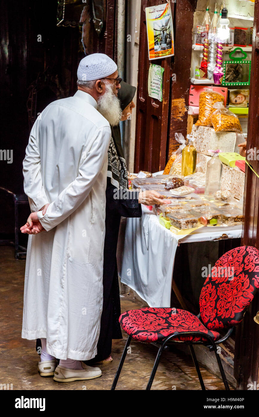 Un homme et sa femme d'acheter des sucreries et des bonbons dans un magasin dans la médina, Fès el Bali, Maroc Banque D'Images