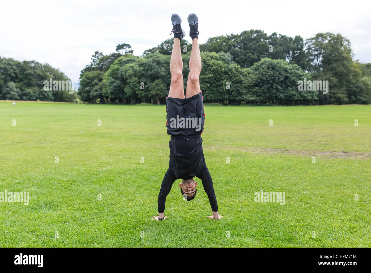 Faire de l'athlète un handstand on meadow Banque D'Images