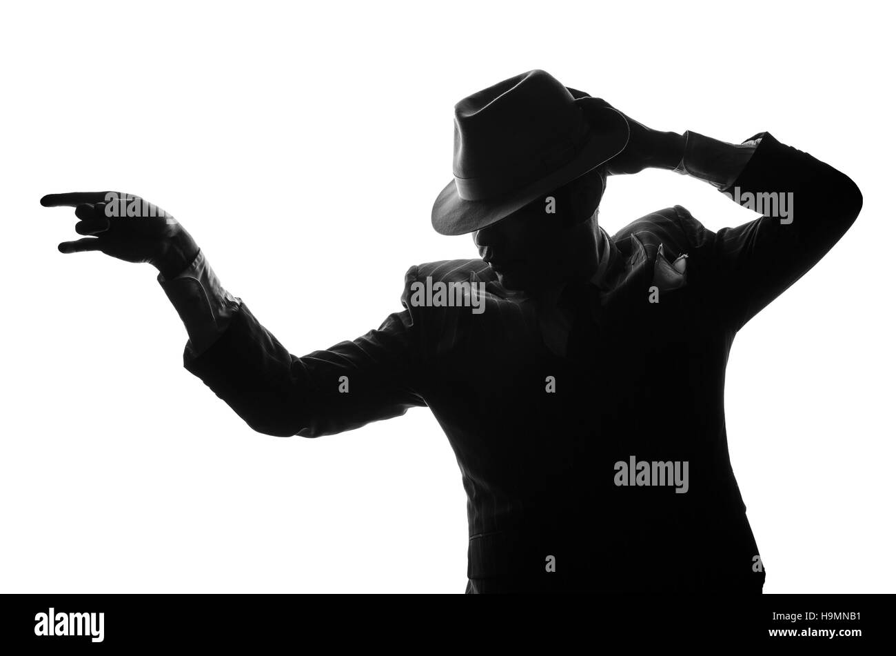 Silhouette de dancing détective privé. Séjour de l'agent d'un côté à l'appareil photo et se présente comme mafieux Al Capone. Scène de foule ou criminel. Studio shot Banque D'Images Silhouette de dancing détective privé. Séjour de l'agent d'un côté à l'appareil photo et se présente comme mafieux Al Capone. Scène de foule ou criminel. Studio shot Banque D'Images