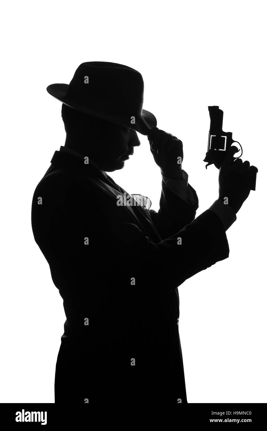 Silhouette de détective privé avec un pistolet dans la main droite. Séjour de l'agent d'un côté à l'appareil photo et se présente comme mafieux Al Capone. Scène criminelle. Studio shot Banque D'Images Silhouette de détective privé avec un pistolet dans la main droite. Séjour de l'agent d'un côté à l'appareil photo et se présente comme mafieux Al Capone. Scène criminelle. Studio shot Banque D'Images