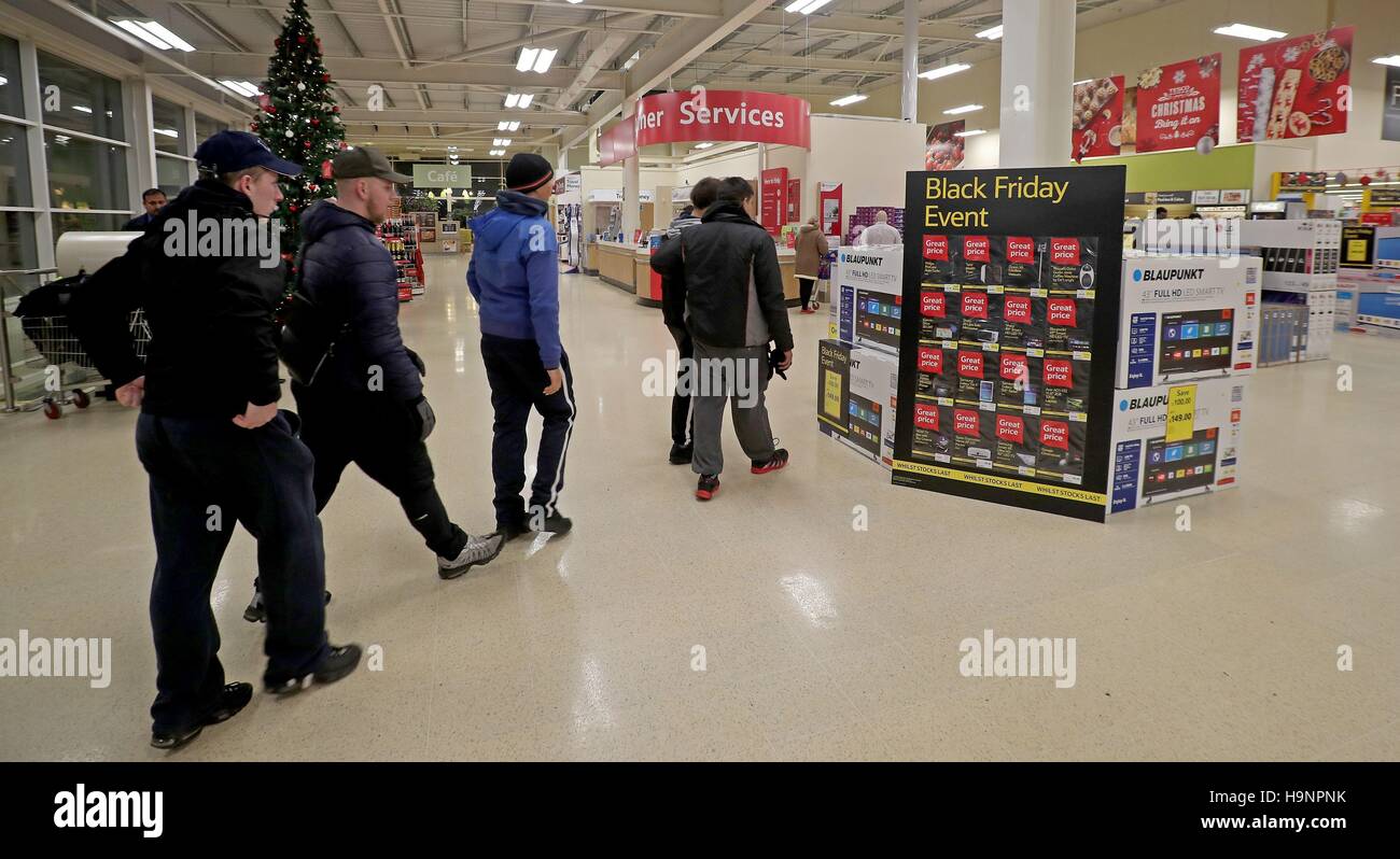 Shoppers entrez le Tesco Magasin supplémentaire à Manchester, à la recherche économique affaires au début de la vente le vendredi noir du supermarché. Banque D'Images