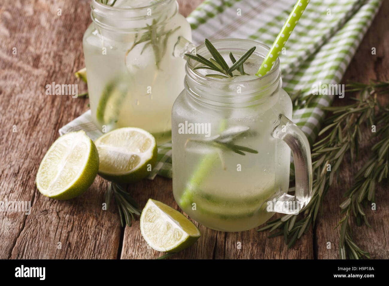 Boisson froide d'été avec de la chaux, de la glace et de romarin close up dans un bocal en verre sur la table. L'horizontale Banque D'Images