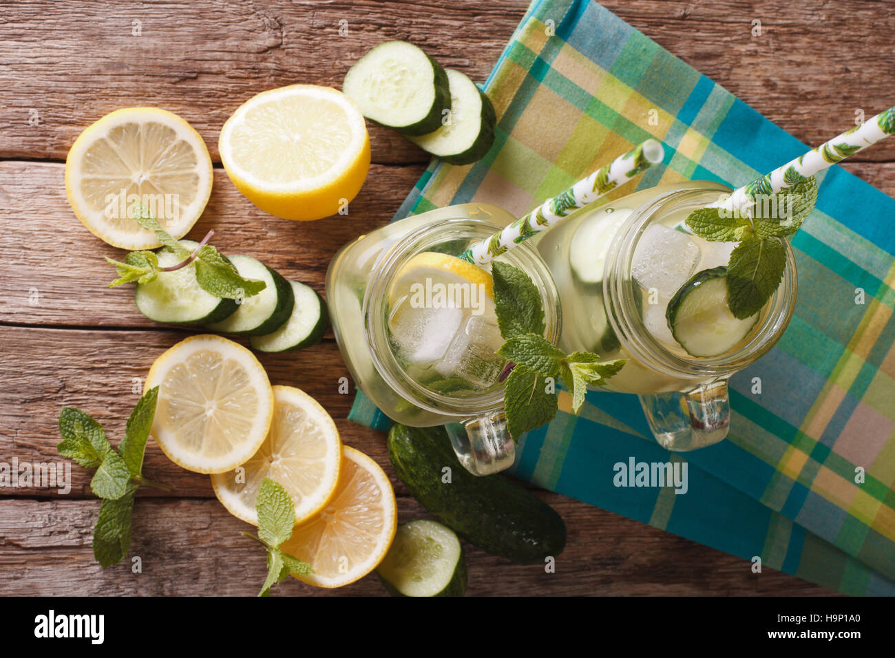 L'eau froide avec le concombre, le citron, la glace et la menthe close up dans un bocal en verre sur la table. Vue du dessus horizontale Banque D'Images