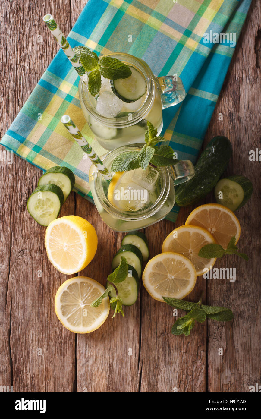 Boisson d'été avec le concombre, le citron, la glace et la menthe close up dans un bocal en verre sur la table. vertical Vue de dessus Banque D'Images