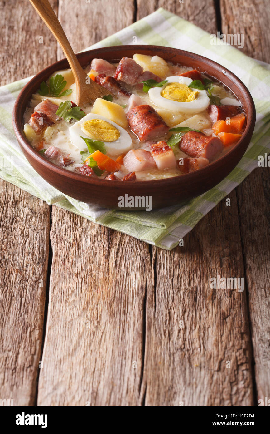 Soupe Zurek polonais avec de la saucisse, les légumes et les œufs dans un bol sur la table verticale. Banque D'Images