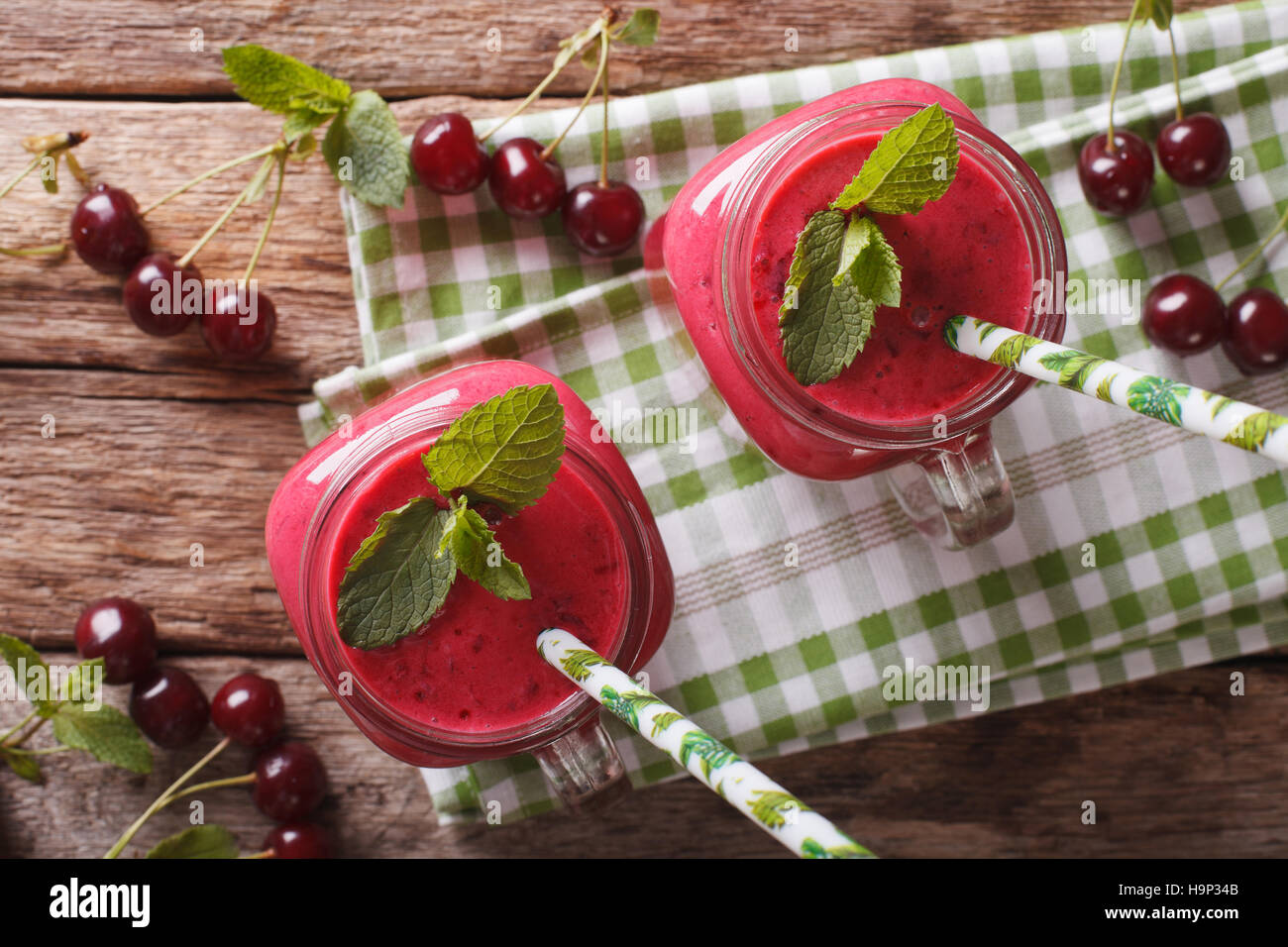 Smoothie cerise fait maison avec de la menthe en pot de verre macro sur la table horizontale vue du dessus. Banque D'Images