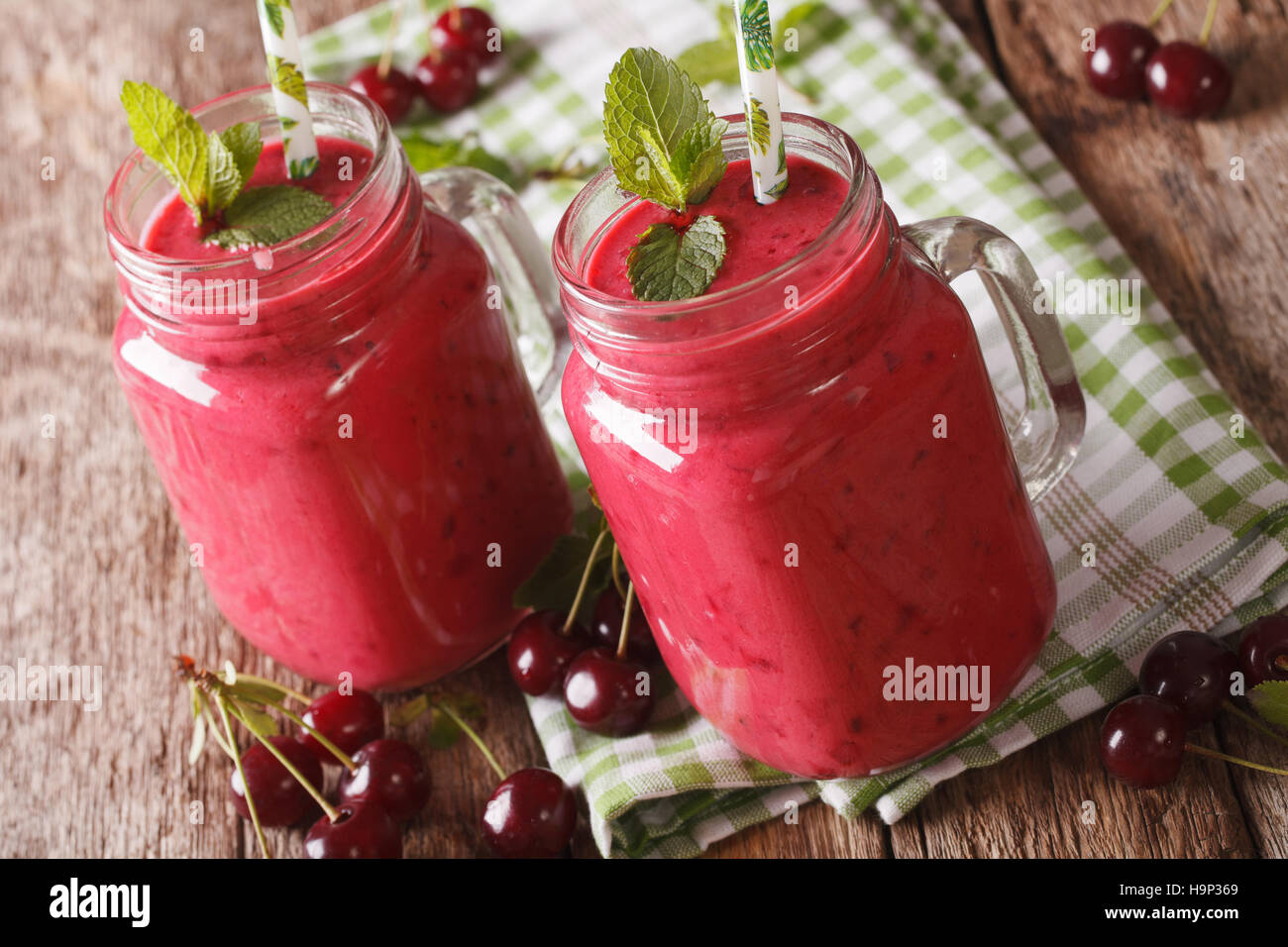 Smoothie cerise fraîche à la menthe dans des bocaux en verre sur la table horizontale. Banque D'Images