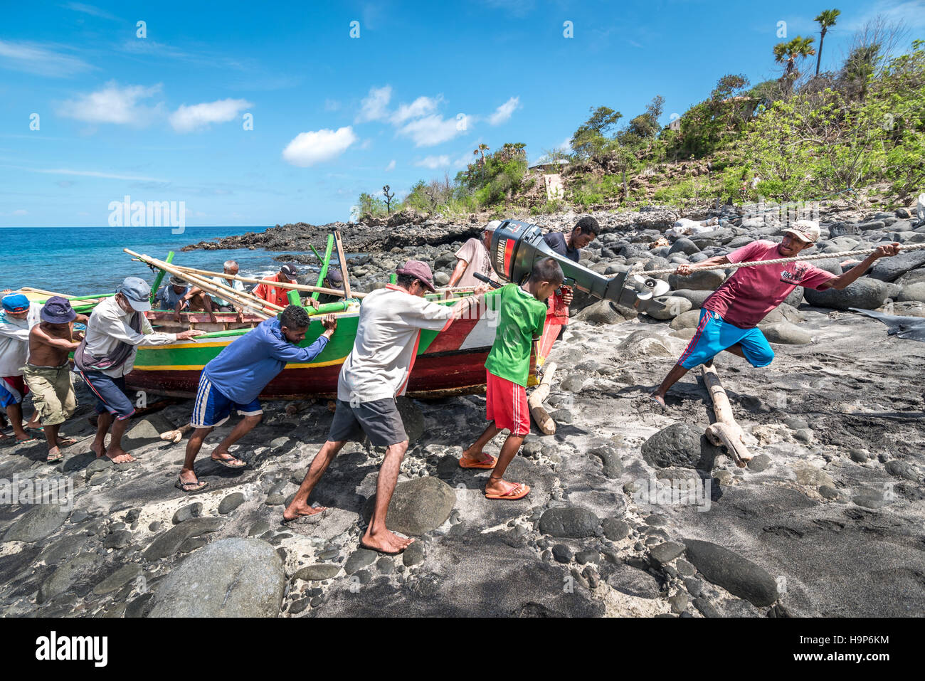 Personnes tirant un bateau ensemble sur une plage rocheuse appelée 'Lamalera B' dans le village de chasse à la baleine de Lamalera à Lembata, à Nusa Tenggara est, Indonésie. Banque D'Images