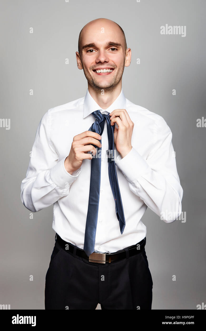 Portrait of young smiling businessman tying une cravate. Banque D'Images