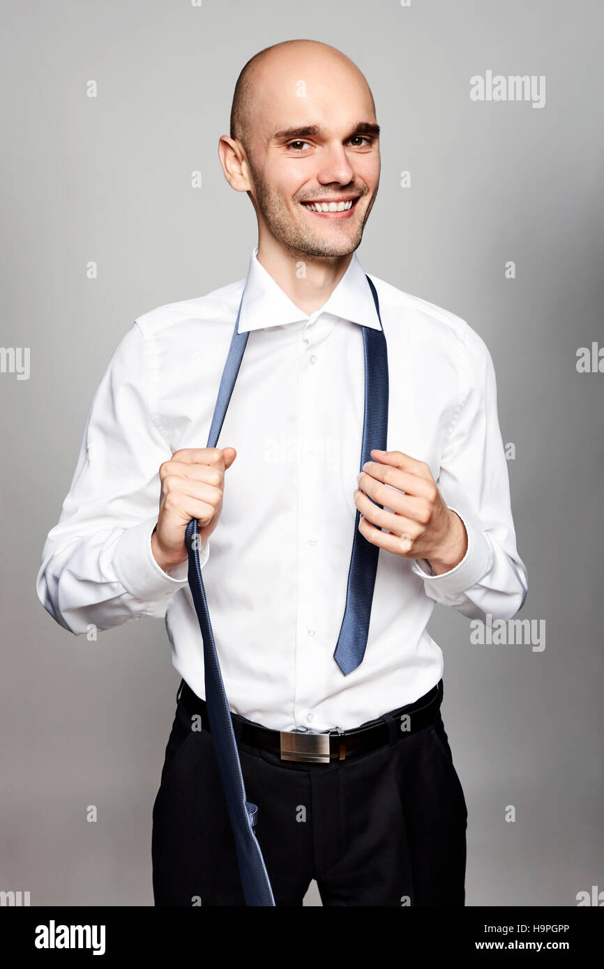 Portrait of young smiling man taking off une cravate. Banque D'Images