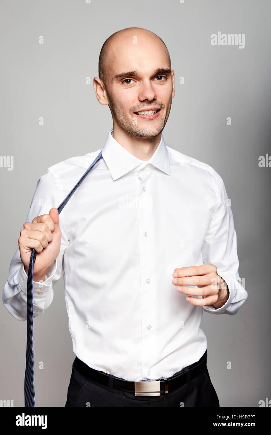 Portrait of young man taking off une cravate. Studio shot, fond gris. Banque D'Images