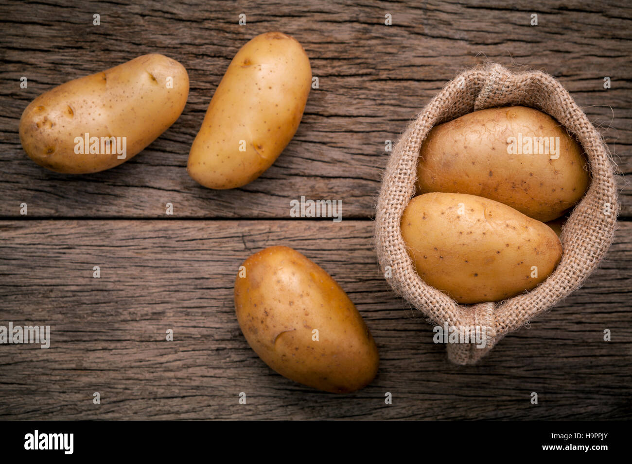 Des pommes de terre biologiques frais dans le chanvre nom sac sur rustique en background Banque D'Images
