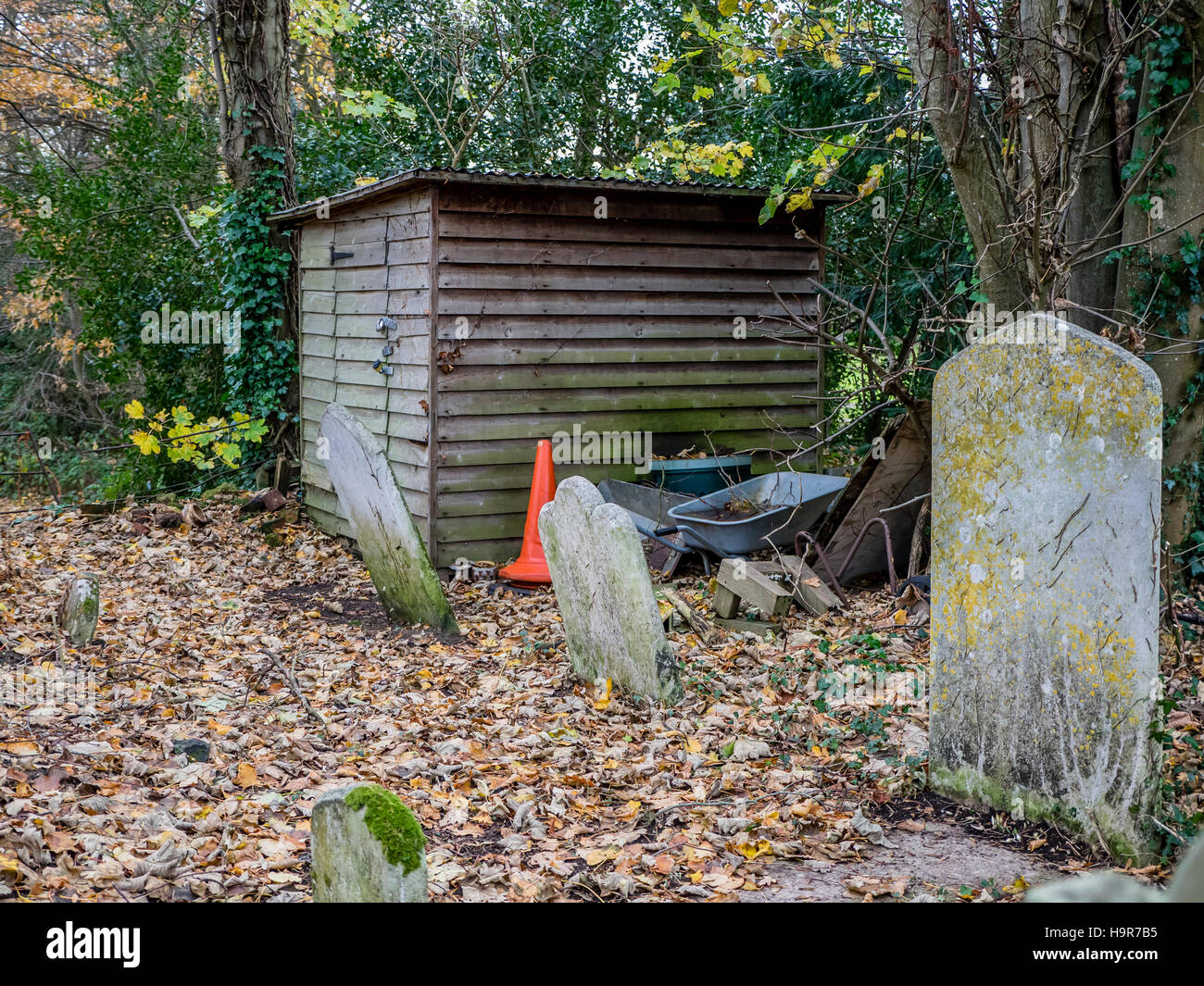 Ancien hangar en bois au coin de cimetière parmi des pierres tombales Banque D'Images