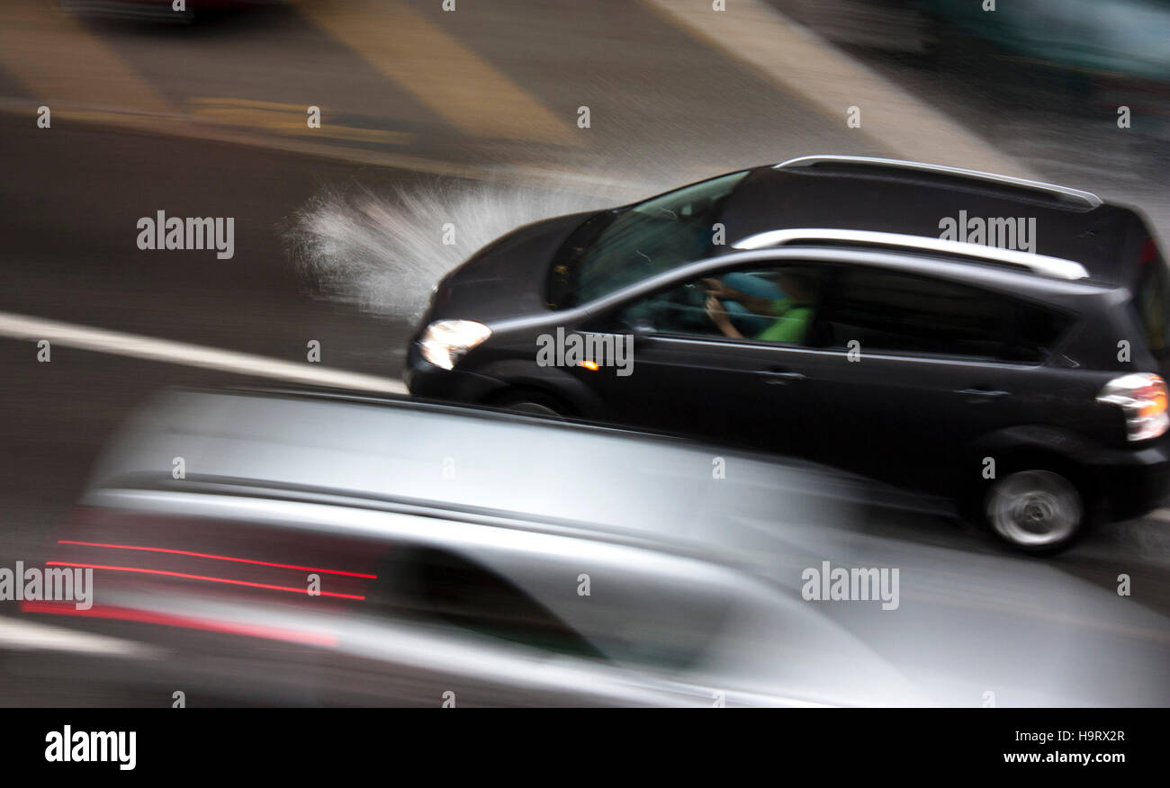 Conduire des voitures dans la rue de la ville avec une faible visibilité et les projections d'eau. Banque D'Images