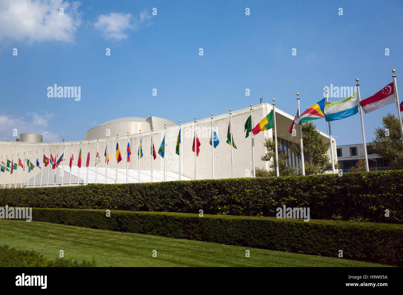 Bâtiment de l ' Assemblée générale des Nations Unies avec des drapeaux du monde qui flottent devant une journée ensoleillée avec un ciel bleu - First Avenue, New York City, NY, USA Banque D'Images