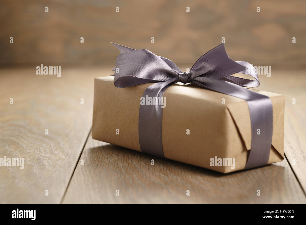 Papier artisanal rustique boîte-cadeau avec ruban lilas sur bow table bois Banque D'Images