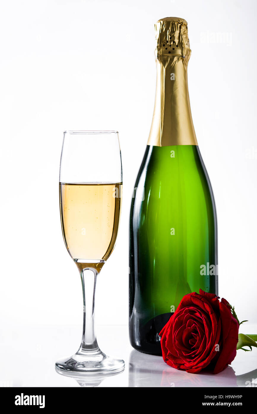 Bouteille de champagne, tasse et rose rouge sur fond blanc Banque D'Images
