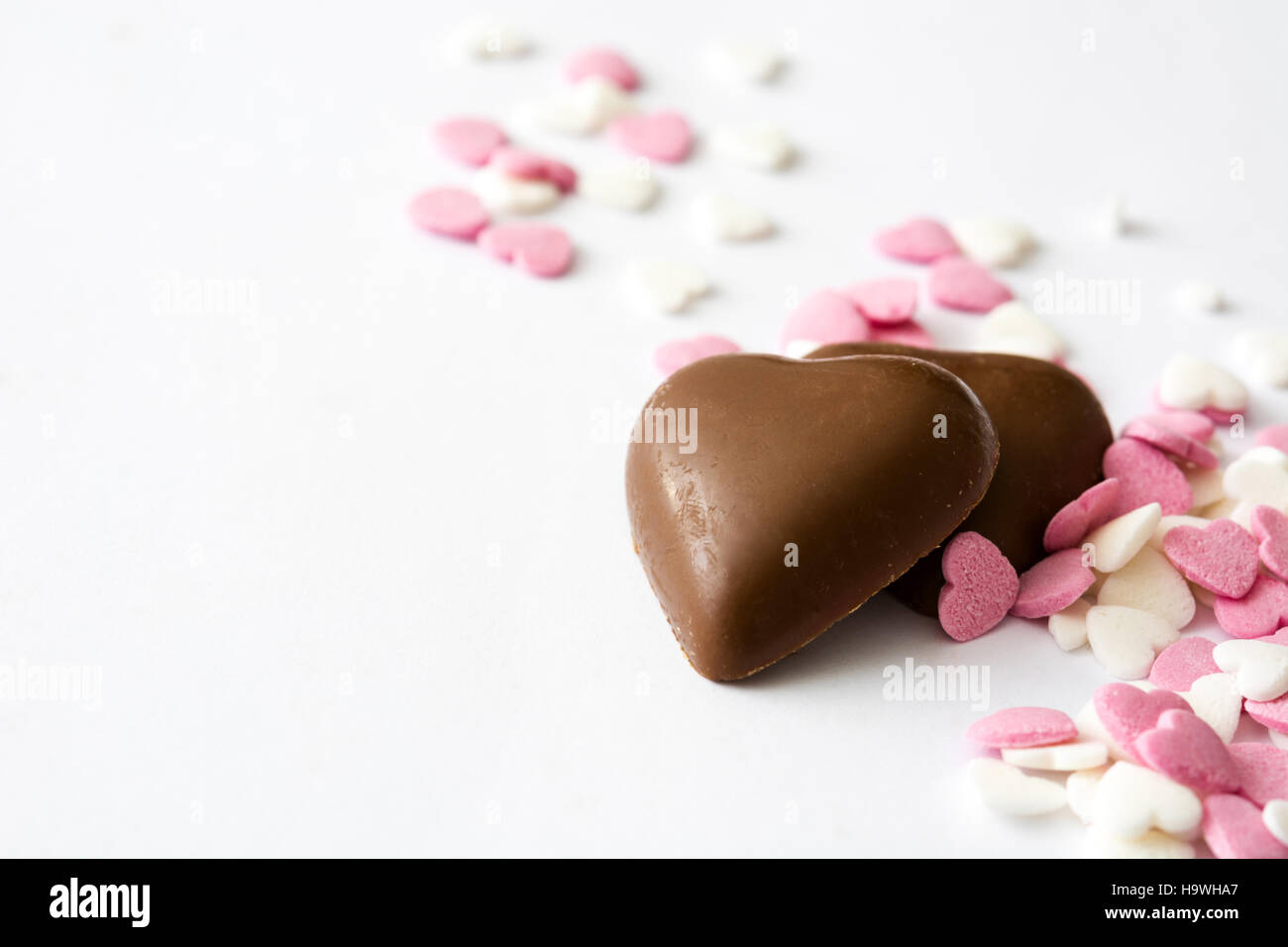 Bonbons de chocolat noir avec forme de coeur et bonbons sur fond blanc Banque D'Images