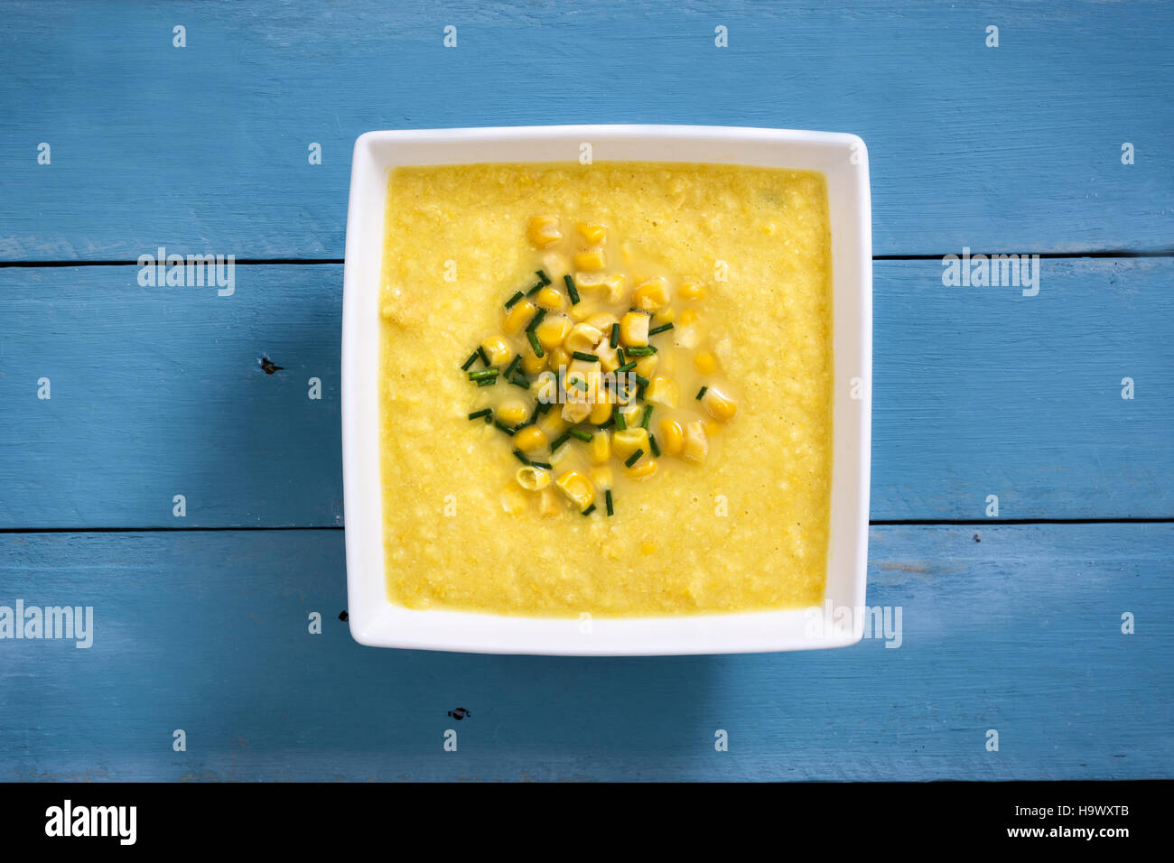 Soupe de maïs dans un bol blanc sur bleu fond de bois.copyspace Banque D'Images